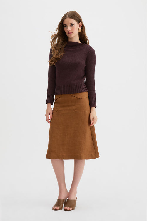Claude Knit and Kingma A-Line Skirt. A woman modeling a dark brown draped knit sweater and a rust linen A-line skirt against a plain white studio background.