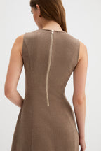 Laverne Dress, rear view of a woman wearing a sleeveless taupe-brown dress with a vertical gold-tone zipper at the back, shown against a light gray studio background.