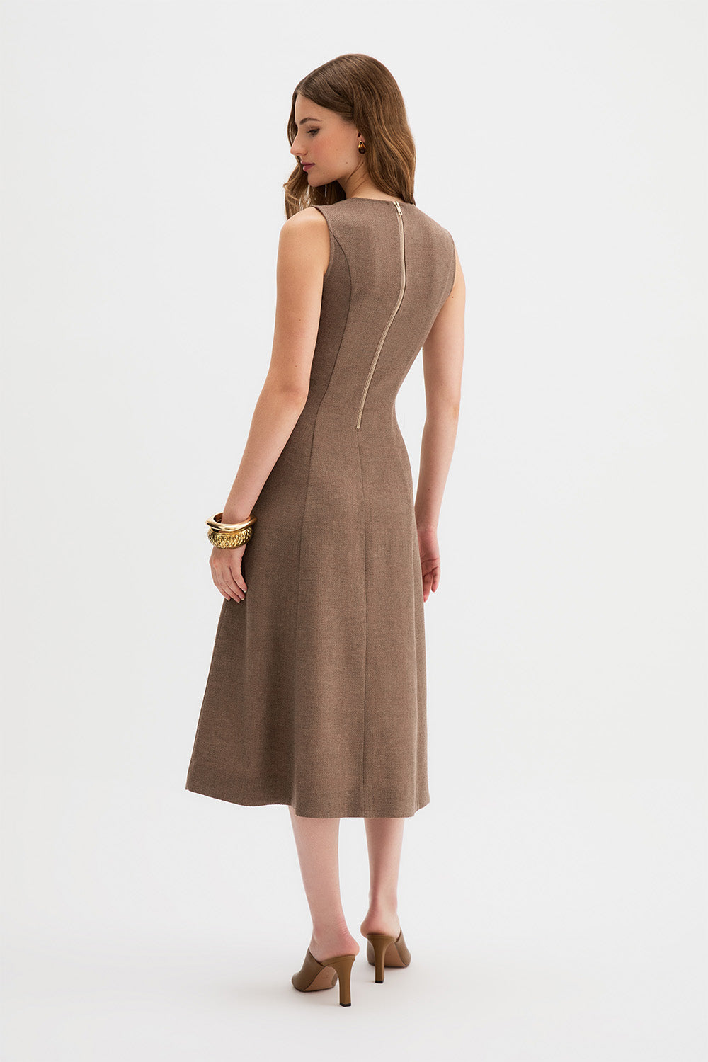 Laverne Midi Dress, a woman modeling a sleeveless taupe-brown midi dress from the back, showing a central seam detail, against a plain white studio background.